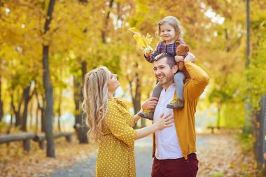 Ailesi sonbaharda sarı parkta bebekle oynuyor..