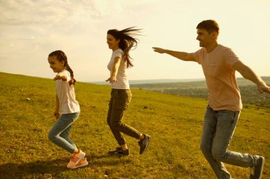 Anne, baba ve küçük çocuğun dağlarda koştuğu neşeli bir aile. Çocuklu aileler uçak oyunu oynarken eğleniyor