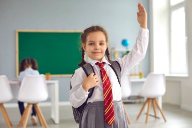 Üniformalı şirin bir kız. Sınıftaki derslerine cevap vermeye hazır. Okuldaki birinci sınıf öğrencisinin portresi.