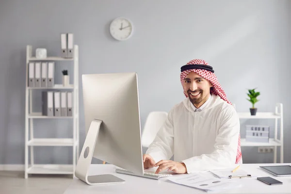 Араб, работающий над анализом печатания за столом с компьютером в офисе . — стоковое фото
