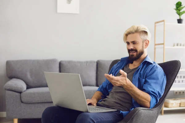 Guy spricht online zu Hause. Fröhliche männliche Freiberufler unterhalten sich per Laptop im Videochat. — Stockfoto