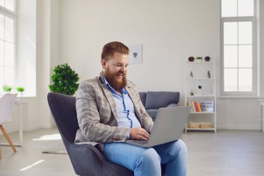 Merkez büroda çalışıyorum. Komik şişman adam dairede dizüstü bilgisayar kullanıyor..