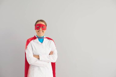 Süper kahraman kostümlü bir doktor gri arka planda bir klinikte çalışıyor..