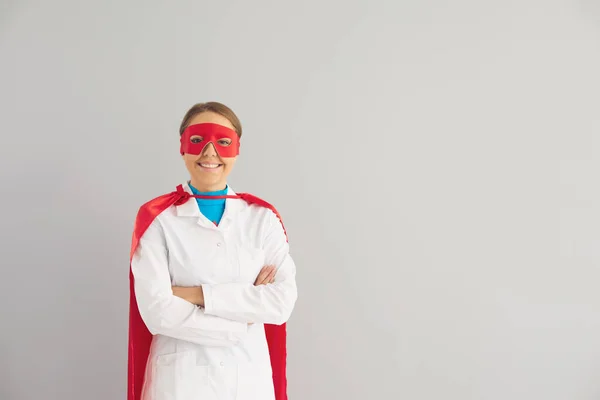 Лікар в костюмі супергероя працює в клініці на сірому фоні . — стокове фото