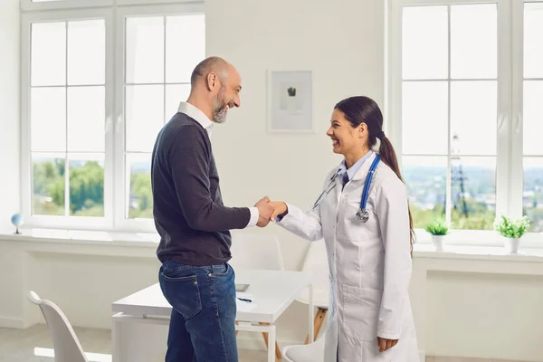 Médico ou enfermeira apertando as mãos com um paciente em pé em uma clínica do hospital . — Fotografia de Stock