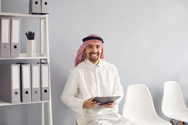 Арабський чоловік з чорною сумкою, що посміхається в офісі. — стокове фото