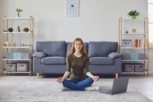 Calm girl meditating or doing yoga to online video tutorial. Woman practicing breathing or relaxation exercises at home — Stock Photo, Image