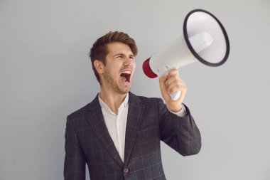 Stylish executive man screaming with loudspeaker on gray background clipart