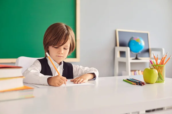 Muchacho serio dibujando durante la clase de arte en la escuela, espacio vacío. Estudiante de primer grado durante la clase — Foto de Stock