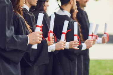 Bir grup mezunun elindeki diploma ların parşömenleri.