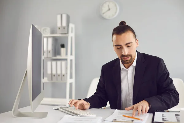 Businessman in a black jacket works. Analyzes at the computer in the office.