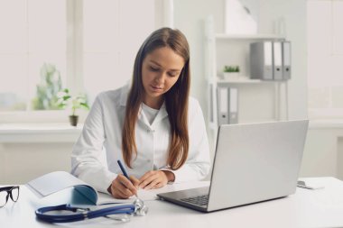 Çevrimiçi tıbbi danışmanlık. Hastanedeki dizüstü bilgisayarında hastayla görüntülü konuşma yapan doktor ilaç formunu yazdı.