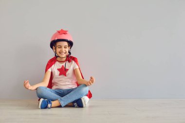 Nilüfer pozisyonunda oturmuş gülen komik bebek süper kahraman..