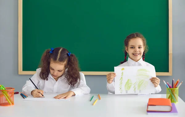 Kislányok rajzolnak az iskolában, űrszöveget másolnak. Imádnivaló gyerekek az osztályteremben. — Stock Fotó