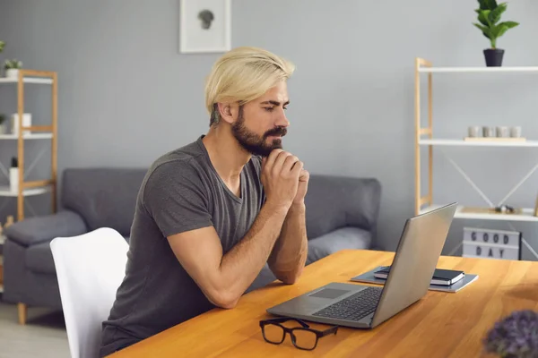 Mladý muž pracuje na laptopu v domácí kanceláři. Millennial muž dirigování on-line konference nebo obchodní jednání — Stock fotografie