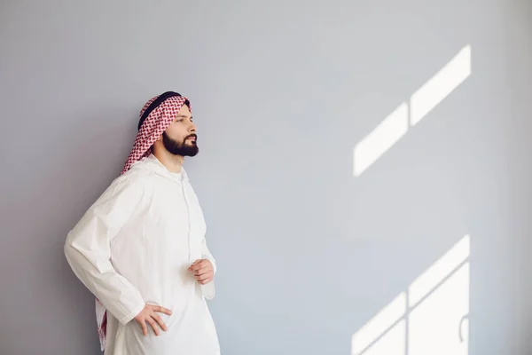 Confident arab man looks up over gray background