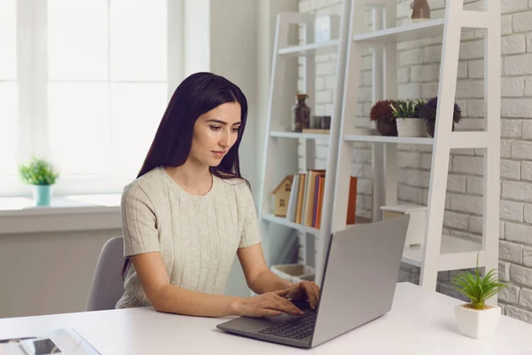 Concepto de trabajo o educación en línea. Hermosa chica joven usando ordenador portátil en la oficina en casa, espacio vacío —  Fotos de Stock