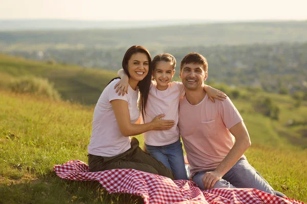 Vreugdevolle familie ontspannen op picknickdeken in de bergen. Schattig meisje lachen met haar ouders op zomerse dag op het platteland — Stockfoto