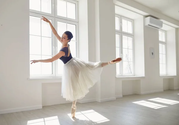 Балерина. Молодой грациозный балетный танцор репетирует спектакль в белой студии с окнами . — стоковое фото