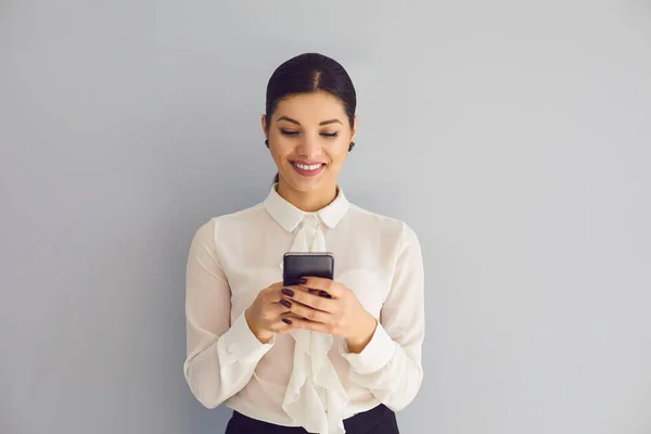 Feliz elegante jovem empresária usando smartphone em segundo plano — Fotografia de Stock