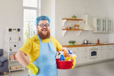 Önlüklü, sakallı komik şişman adam evdeki odayı temizliyor..