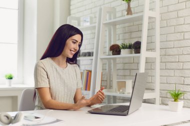Dost canlısı iş kadını ev ofisinde dizüstü bilgisayarla konferans veriyor. Çevrimiçi webinara katılan kız öğrenci
