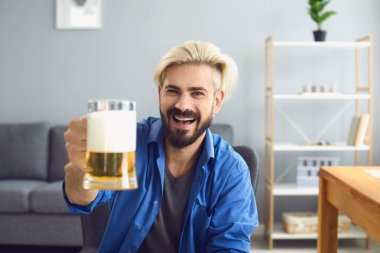 Birası olan neşeli bir adam, internetten erkek arkadaşlarıyla konuşuyor. Web kamerasında arkadaşlarıyla kutlama yapan yakışıklı adam.