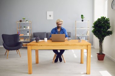 Mesafe çalışması ya da eğitim. Şirket çalışanı evdeki işi için dizüstü bilgisayar kullanıyor. Genç adam iş videosu çekiyor.