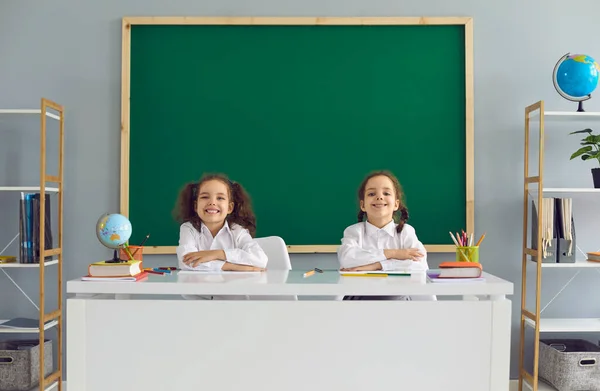 Kembali ke sekolah. Anak-anak sekolah yang positif duduk di meja kelas. — Stok Foto