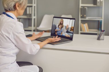 Doktor hatta. Çocuklu anne evdeki video konferansını kullanarak doktorlarla konuşuyor..