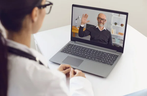 Lekarz i pacjent online. Starszy mężczyzna w okularach rozmawia z lekarzem używając wideokonferencji na laptopie. — Zdjęcie stockowe