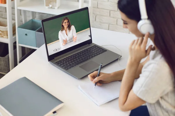 Online-Lehrer. Studentin mit Kopfhörer hört Video-Chat-Vorlesung eines Hochschullehrers hat einen Computer zu Hause. — Stockfoto