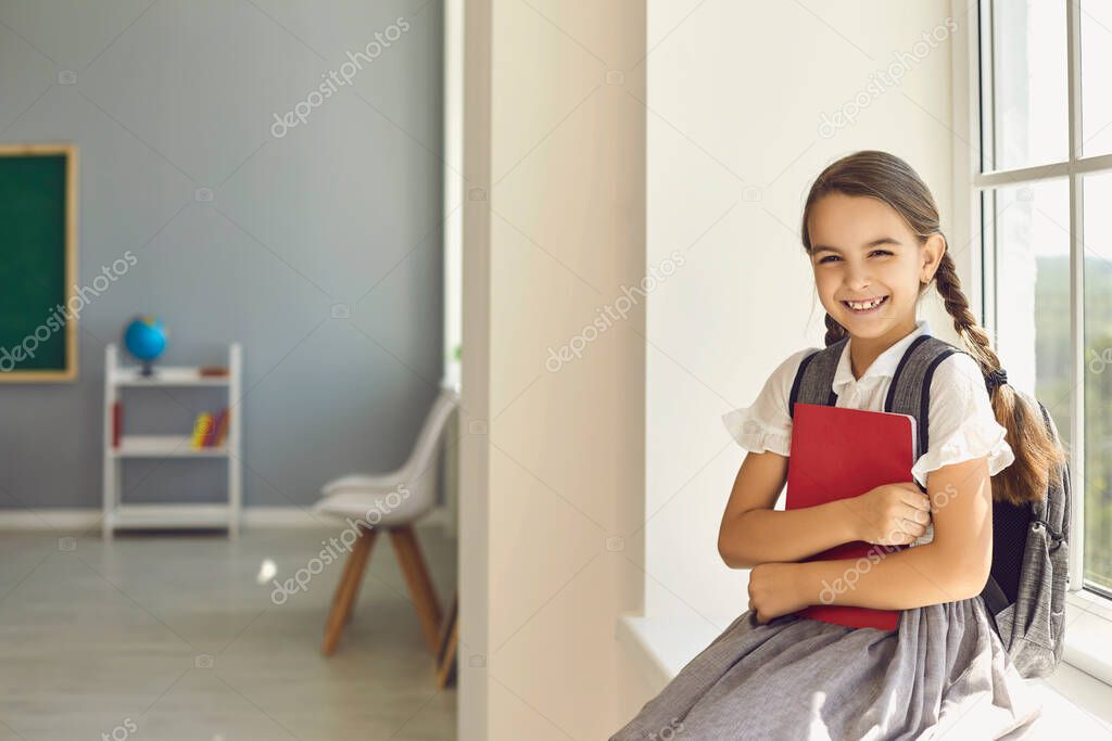 Back to school. Schoolgirl with a backpack and books in hands l in the classroom