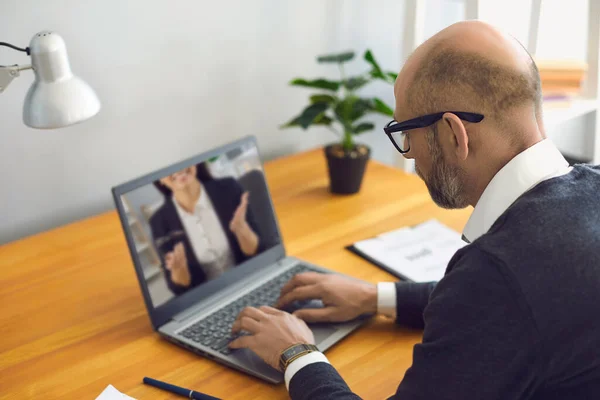 Trabalhar online. O homem sênior que trabalha comunica-se usando o bate-papo vídeo do portátil com o escritório sentado do sócio em casa . — Fotografia de Stock