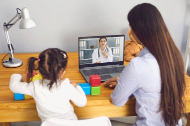 Aile doktoru hatta. Anne ve kızı, doktor muayenesini dinleyin. Odada bir video konferansı var..