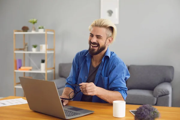 Smějící se muž na volné noze pomocí notebooku videokonference doma. — Stock fotografie