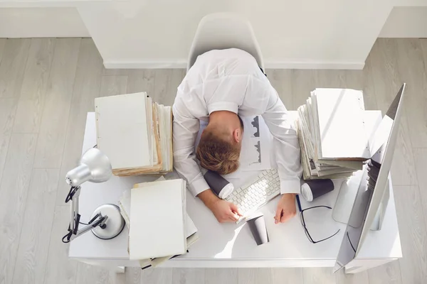 Trött upptagen affärsman sover vid ett bord med en dator. — Stockfoto