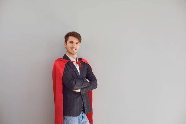 Homme heureux en costume de super-héros sourire sur fond gris. — Photo