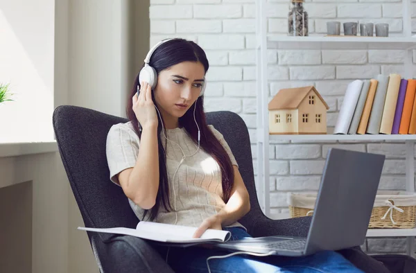 Woman with laptop and headphones taking online educational course at home. Remote employee participating in conference — Stock Photo, Image