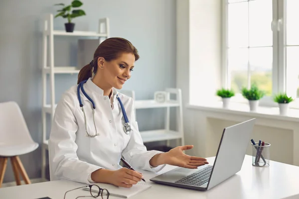 Giovane dottoressa che parla con la paziente online dallo studio medico. Medico consulente cliente su video chat laptop in ospedale — Foto Stock
