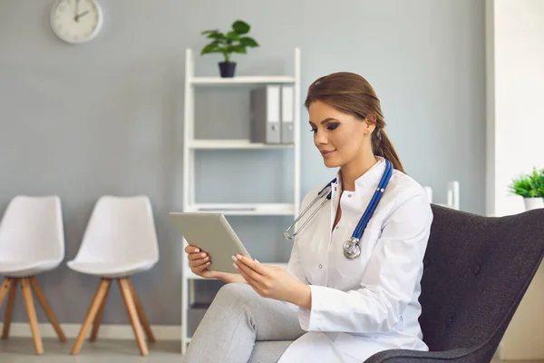 Medico donna con tablet parlare con cliente online dalla clinica. Medico professionista in videoconferenza con paziente — Foto Stock