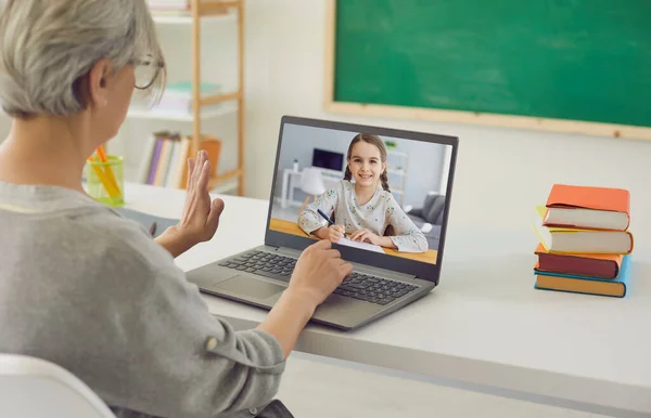 Evde eğitim. Sınıftan küçük bir kızla konuşan yetişkin bir öğretmen. Öğrenciyle çevrimiçi iletişim kuran özel öğretmen