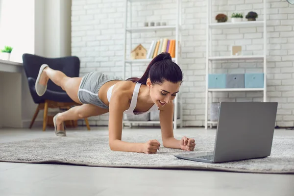 年轻的黑人在家里锻炼，在笔记本电脑上观看健身训练录像。侧视图. — 图库照片