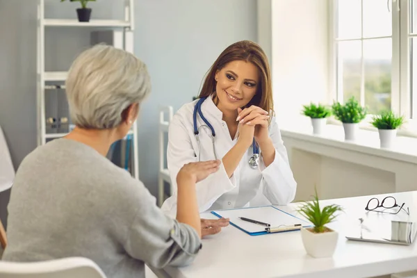 Senior lady on visit to doctor at hospital, copy space. Young medical specialist consulting mature patient at clinic — Stock Photo, Image