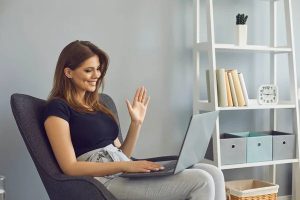 Young female freelancer communicating with client via video call on laptop. Tutor giving online class from home office — Stock Photo, Image