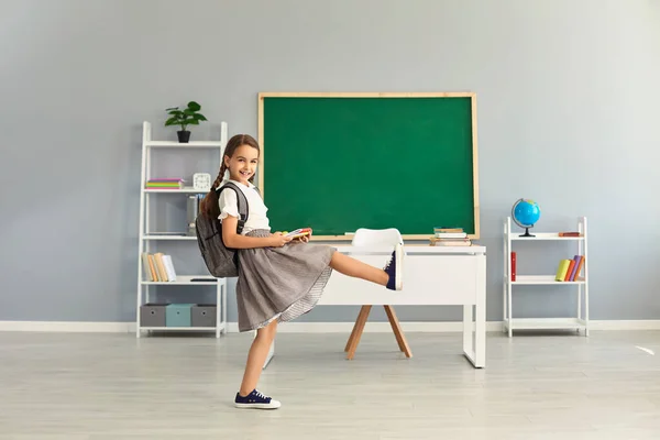 Jolie fille en uniforme avec sac à dos marchant dans la salle de classe, copier le texte de l'espace. Élève primaire débutant la nouvelle année scolaire — Photo