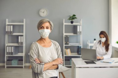 Klinikte koruyucu maske takan üst düzey bir kadın..