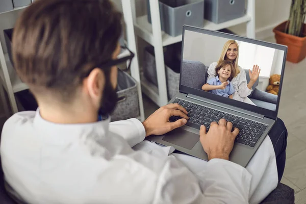 Médico consulta uma mulher com uma criança usando uma câmera web de computador no escritório de uma clínica médica . — Fotografia de Stock