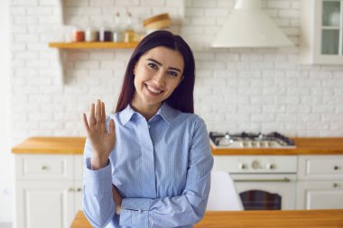 Modern mutfaktayken memnun bir kadın merhaba diyor.