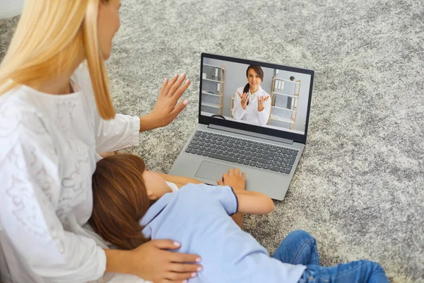 Jovem mãe e menino doente usando o serviço médico on-line em casa, consultando pediatra através de vídeo chat — Fotografia de Stock